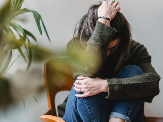 unrecognizable upset lady embracing knees sitting on chair